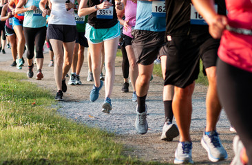 Legs of runners on a dirt path running a 5K race