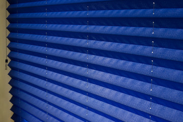Pleated blinds XL , blue color, with 50mm fold closeup in the details on the window in the interior. Home blinds - modern bottom up privacy shades on apartment windows.