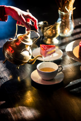 woman pours tea during a tea party with a raw cake