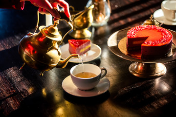 woman pours tea during a tea party with a raw cake