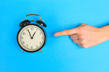  Beautiful young woman's hands with alarm clock  on pastel  background.