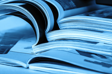 Pages of an open magazine, close-up, toning in blue. Selective focus.