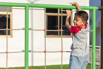 Portrait image of 5-6 years old boy. Happy Asian child boy play the toy and climbling the rope at the playground. He smiling. Sport and exercise of kid.