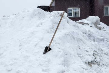 Naklejka premium Siberia. A shovel and a pile of snow. House in the snow to be cleared.