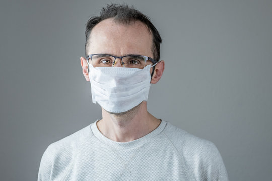 Caucasian man wearing a white medical mask for protection against contagious disease, coronavirus