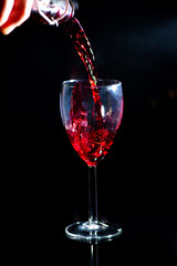 bachelor which pours red wine and spills a little by on a black background