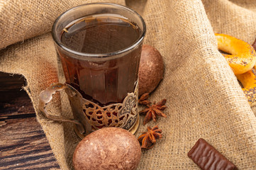 A glass of tea in a vintage Cup holder , chocolate gingerbread and chocolate on a background of textured fabric. Close up.