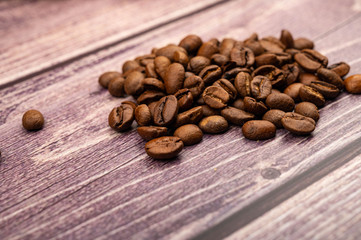 A pile of roasted coffee beans on a wooden background. Close up.