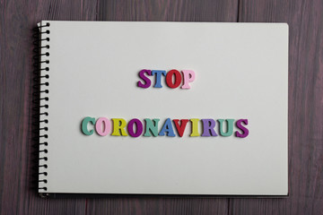 Text Stop Coronavirus wooden letters on notebook on wooden background