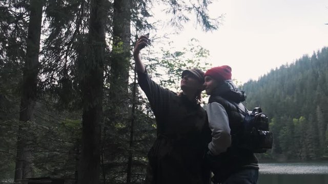 Mother and daughter are doing Selfe on the shore of lake.