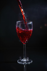 bachelor which pours red wine and spills a little by on a black background