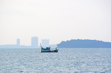 Lonely fishing boat in the sea against the backdrop of the city