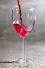 a glass of wine in which red wine is poured on a cement background