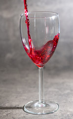 a glass of wine in which red wine is poured on a cement background