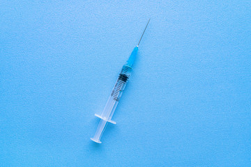 A syringe with a coronavirus vaccine isolated on a blue background with space for text close-up.