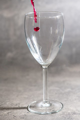 a glass of wine in which red wine is poured on a cement background