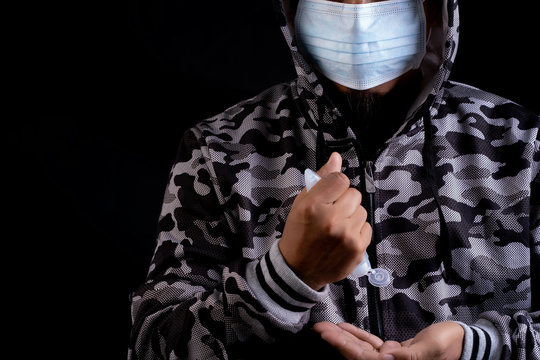 Man with protective mask  is holding  alchol jel bottle  for hand washing on black background.Anti-virus and Anti-COVID 19.Coronavirus.