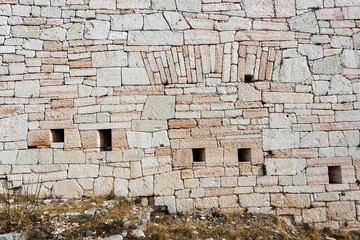 Closeup of an Austrian fortified wall made of irregular stone blocks with arrowslits or loopholes