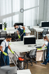 multicultural team of cleaners working in modern open space office