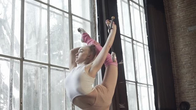 Girl in a loft studio shows exercises with rhythmic gymnastics