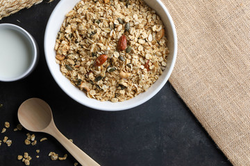 Granola bowl and milk on black background. Top view. Copy space.