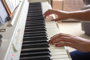 Fototapeta premium Woman practicing lessons on her white electric piano