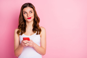 Portrait of inspired positive girl use cellphone look copyspace think thoughts dream dreamy what post on social network account wear white singlet isolated over pink color background