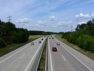 German Autobahn/Highway with cars on a sunny day and high voltage electricity  lines in the...