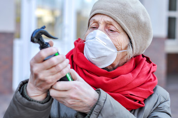 An elderly woman in a respirator reads the instructions for use of the sanitizer antiseptic against...