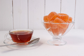 a Cup of tea and citrus marmalade in a candy bowl on a white background