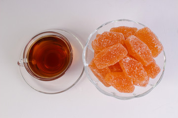 a Cup of tea and citrus marmalade in a candy bowl on a white background
