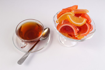 a Cup of tea and citrus marmalade in a candy bowl on a white background