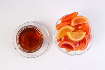 a Cup of tea and citrus marmalade in a candy bowl on a white background