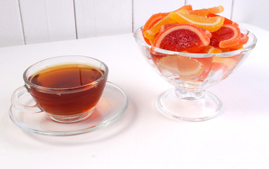 a Cup of tea and citrus marmalade in a candy bowl on a white background