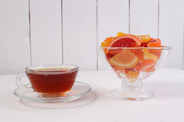 a Cup of tea and citrus marmalade in a candy bowl on a white background