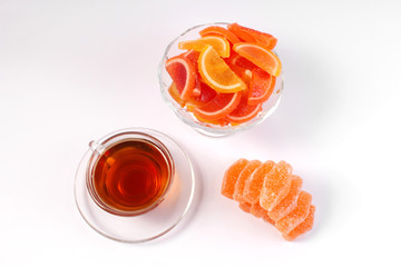 a Cup of tea and citrus marmalade in a candy bowl on a white background
