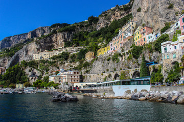 Fototapeta na wymiar View of the town of Amalfi from the jetty with the sea and the colorful houses on the slopes of the Amalfi coast in the province of Salerno, Campania, Italy.
