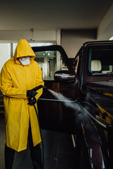 Man in protective suit disinfect a car after during the new coronavirus Covid-19.