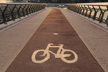 A white bicycle sign on a red color track of bike lane in the middle of New Pedestrian Bridge. Wide...