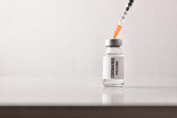 Background with vial and syringe with coronavirus dose on table