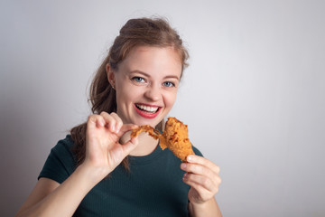 Smiling young Caucasian woman girl holding eating fried chicken  drumstick