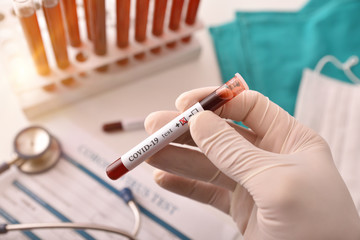 Medical analyst with covid-19 infected blood sample on laboratory table