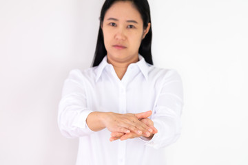 An Asian woman wearing a white shirt is washing her hands with alcohol gel to protect against corona virus or covid 19 on a white background.