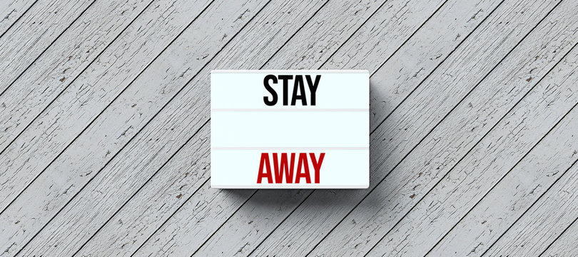 lightbox with text STAY AWAY on wooden background