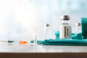 Vial and syringe with coronavirus dose on table hospital front