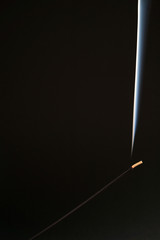 Aromatic stick smokes, isolated. Close-up on a black background. A religious object for a ceremony with a strong smell. The concept of Asia, Buddhism and Prayer