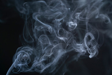 Blue isolated smoke on a black background. The mist is moving up, color of the indigo. The fog dissolves beautifully into different shapes in the air
