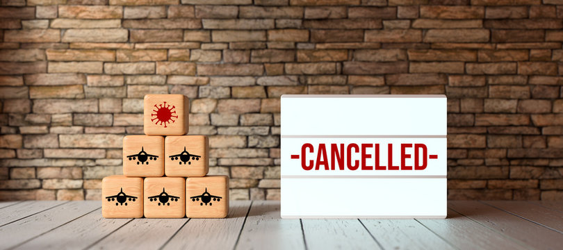 cubes with airplane and virus symbols and lightbox with message CANCELLED in front of a brick wall