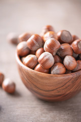 Hazelnuts in wooden bowl on wood textured background. Copy space. Superfood, vegan, vegetarian food concept. Macro of hazelnut, selective focus. Healthy snack.