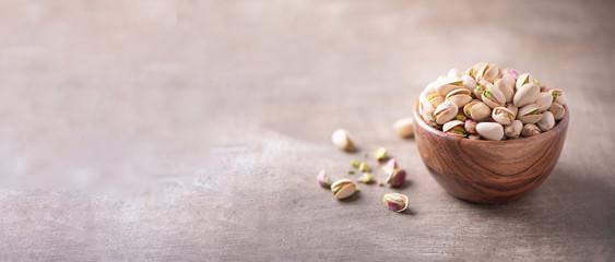 Fototapeta na wymiar Green pistachio nuts in wooden bowl on wood textured background. Copy space. Superfood, vegan, vegetarian food concept. Macro of pistachio nut texture, selective focus. Healthy snack.